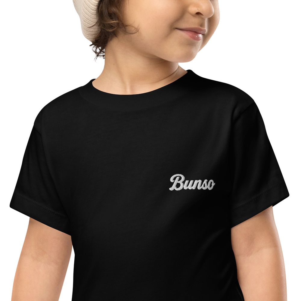 Smiling toddler in a black Bunso (Youngest) toddler t-shirt with white embroidered name on the left chest